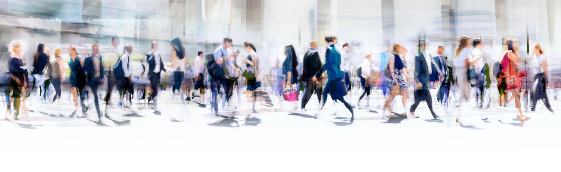 A soft, motion-blurred crowd of professionals walking through a bright building
