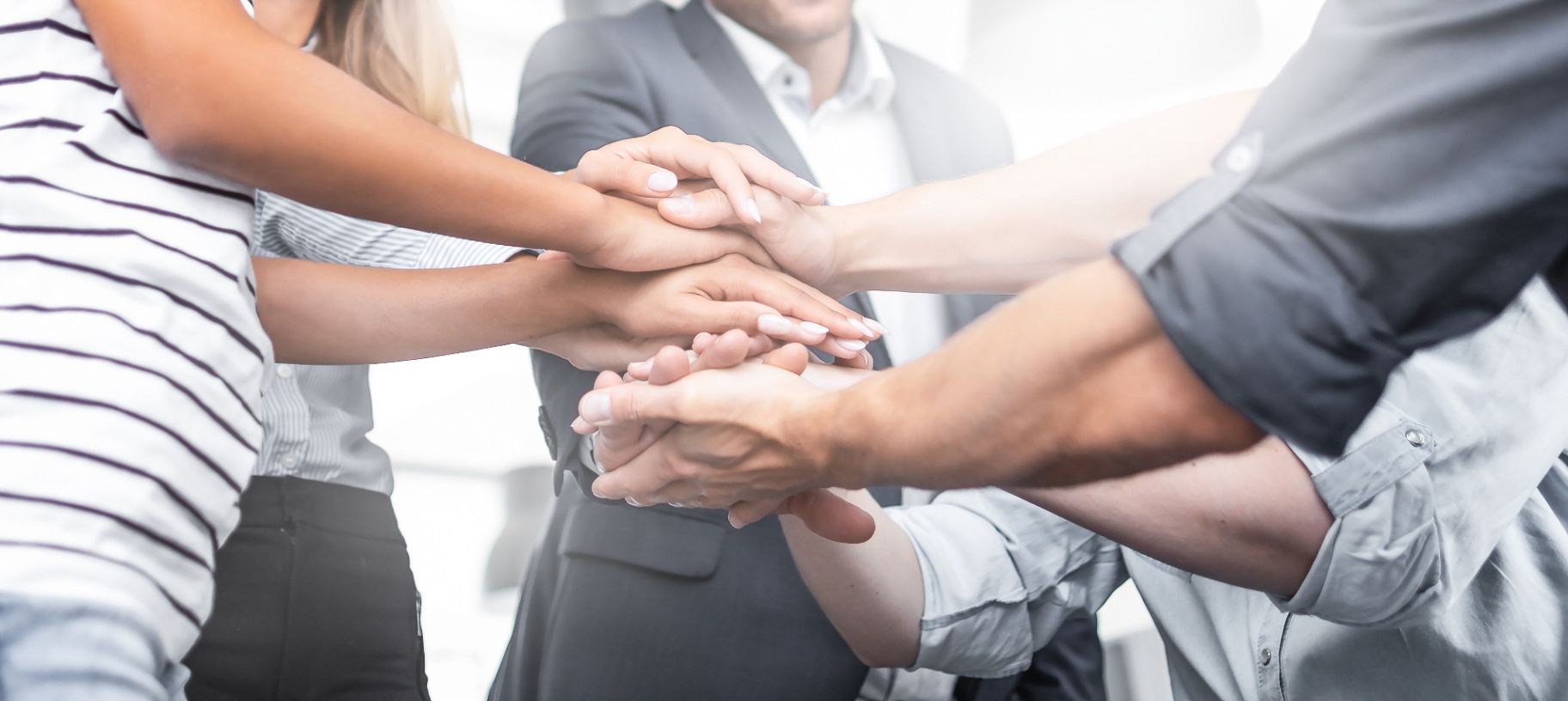 Several colleagues stacking their hands together in a bright office